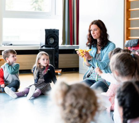 Eine Schulklasse sitzt im Kreis. Die Lehrkraft erklärt etwas.