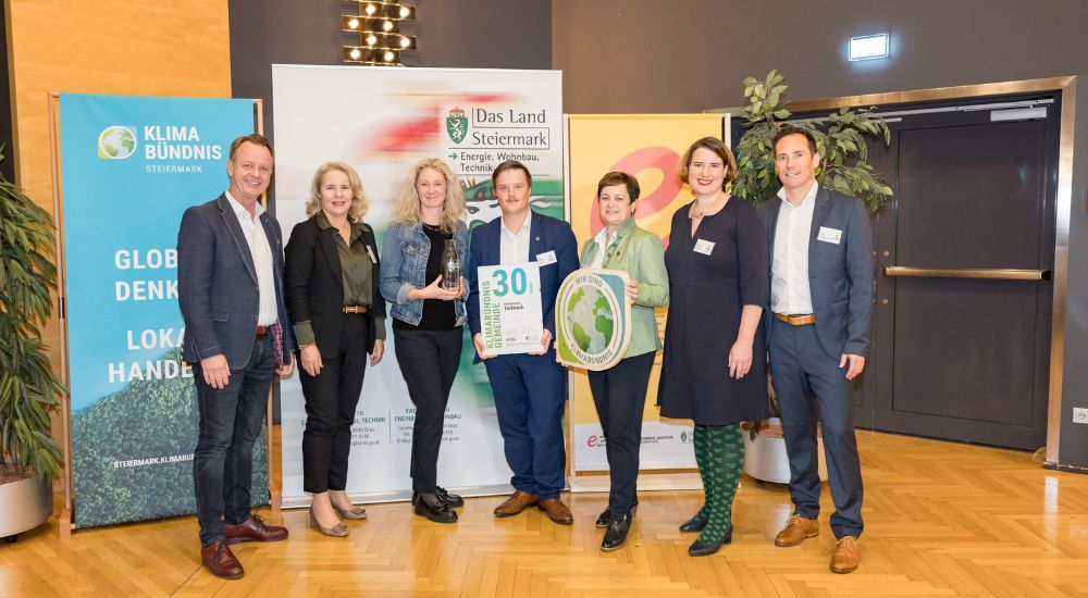 Klimabündnis Auszeichnungsgala: Gemeindevertreter stehen mit Vorständen vor dem Klimabündnis und Land Steiermark Rollup und lächeln. Sie halten die Auszeichnungen in den Händen.