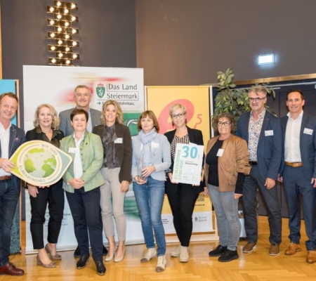 Klimabündnis Auszeichnungsgala: Gemeindevertreter stehen mit Vorständen vor dem Klimabündnis und Land Steiermark Rollup und lächeln. Sie halten die Auszeichnungen in den Händen.
