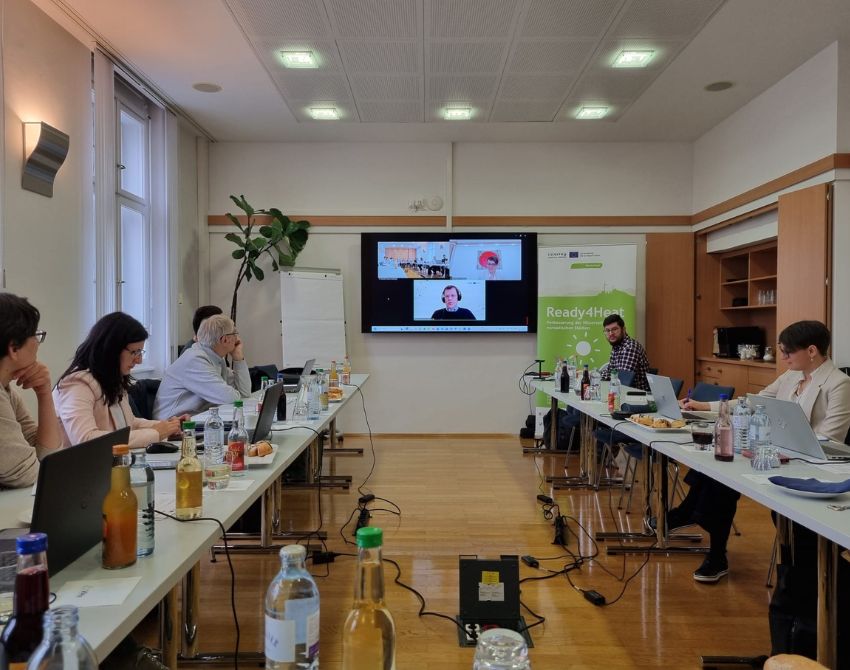 Bild einer Konferenz mit Teilnehmenden vor Ort und online