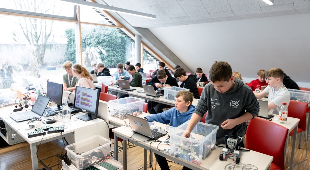 mehrere Jugendliche bauen an Robotern