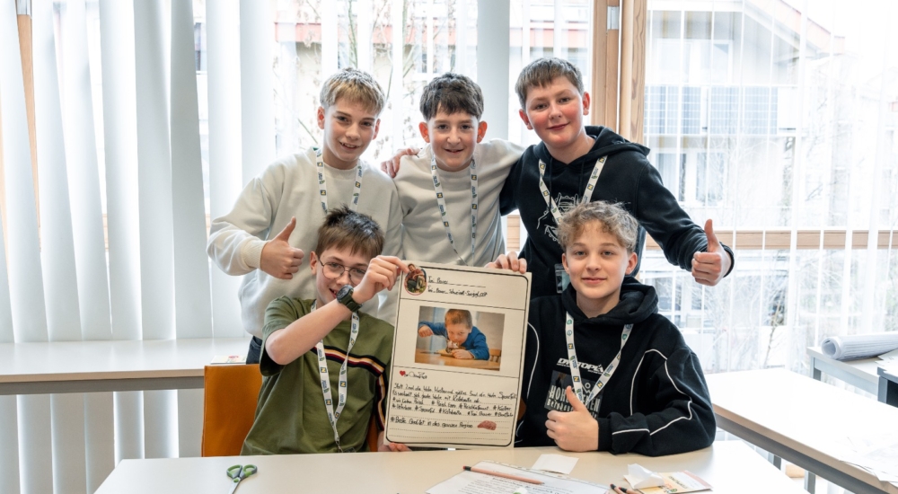 fünf Jungs lachen und halten ihre Arbeit in die Kamera, zwei der Jungs strecken den Daumen in die Höhe