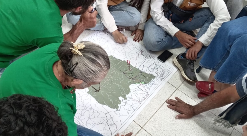 mehrere Menschen sitzen um Karte herum zusammen und besprechen sich