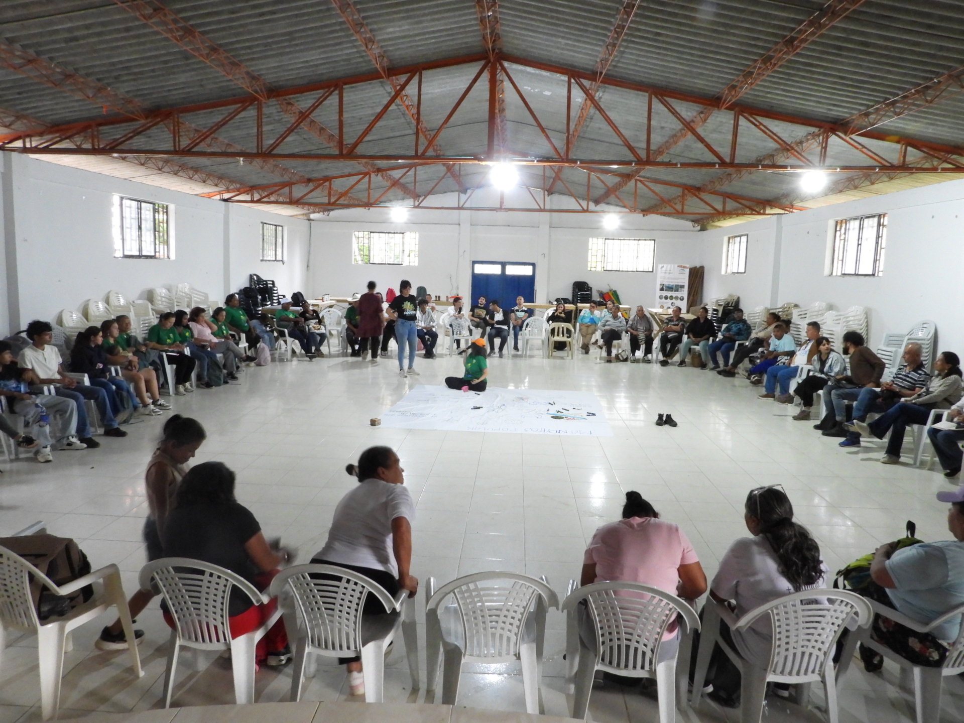 Schule für Bauernrechte in Carmen de Atrato, mehrere Menschen sitzen im Kreis um ein Plakat in der Mitte
