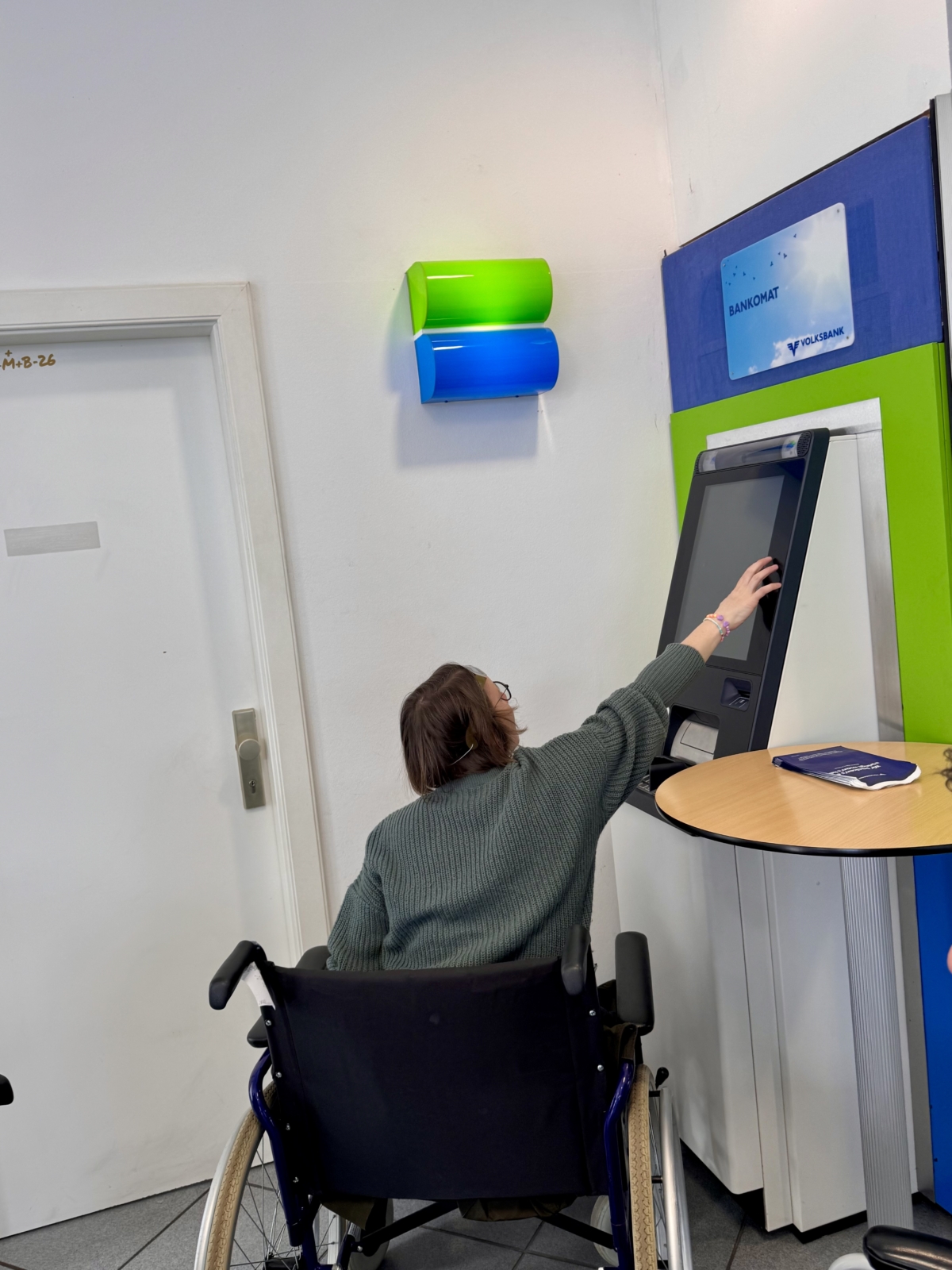 Frau im Rollstuhl versucht Bankautomaten zu bedienen