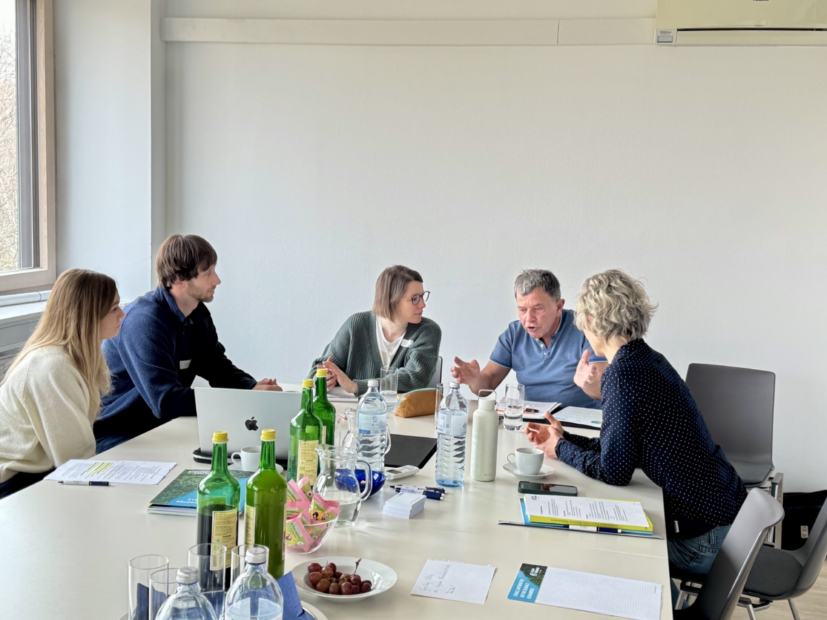 Mehrere Personen sitzen zusammen und diskutieren an einem Tisch