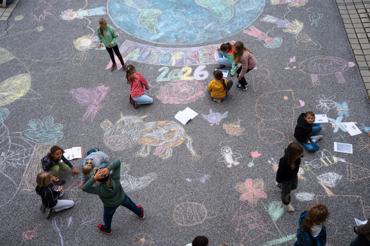 Kinder zeichnen mit Kreiden auf Asphalt
